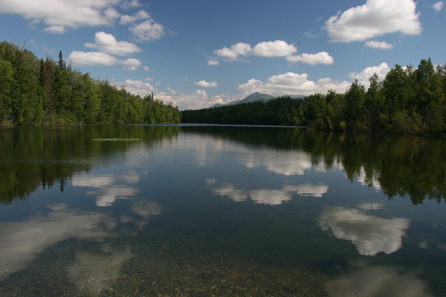 Still lake reflecting clouds and mountains