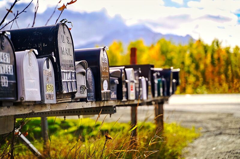 A row of rural mailboxes on a gravel shoulder with golden autumn birch behind