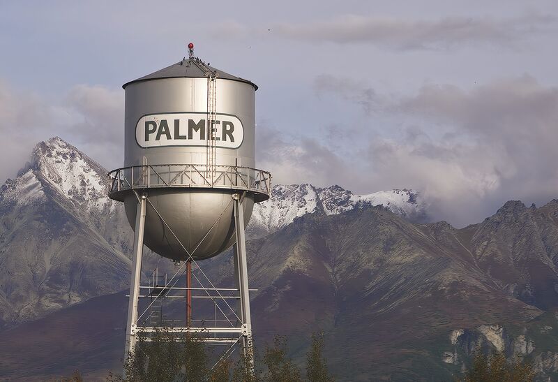 The old Palmer water tower with snow-dusted Pioneer Peak rising behind it